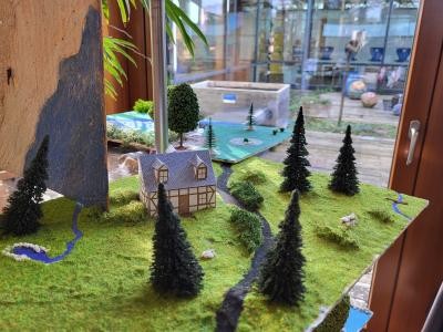 Gebastelte Landschafts-Dioramen mit Tannen und Häuschen.