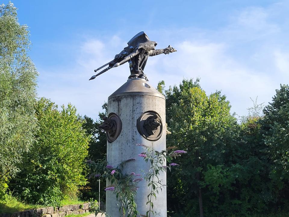 Fliegender Bronze-Ganter auf einer Beton-Stele.