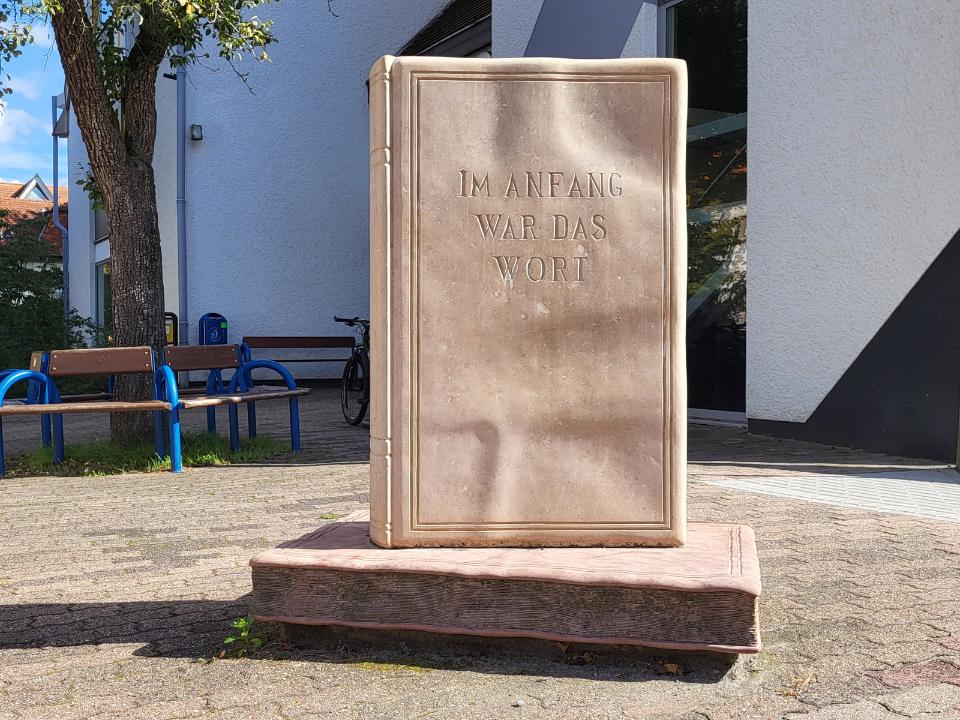 Aufrecht stehendes Buch mit Schriftzug "Am Anfang war das Wort".