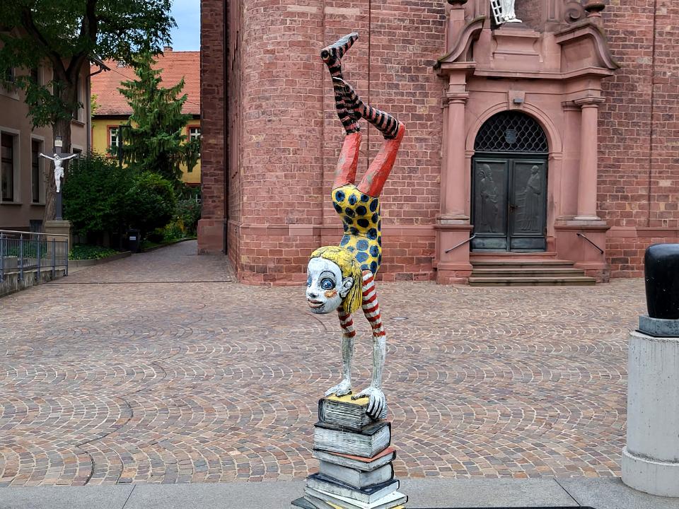 Bunte Figur, im Handstand auf einem Stapel Bücher.