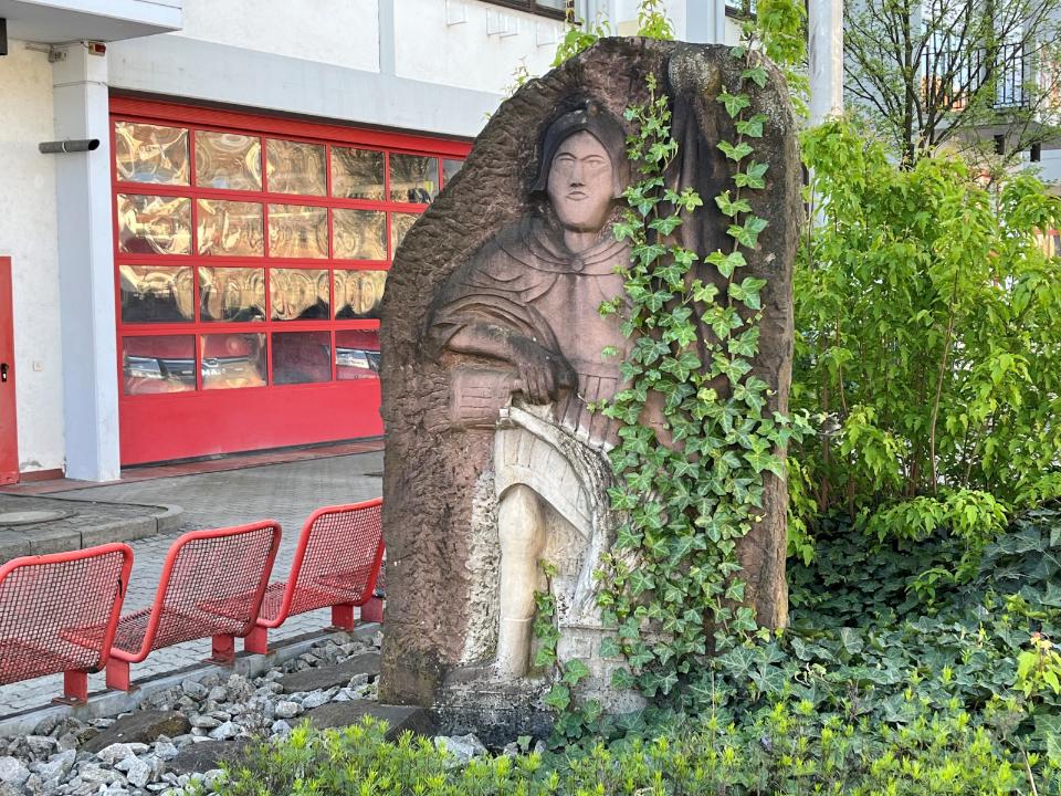 Brunnenbild aus Sandstein, von Efeu umrankt.