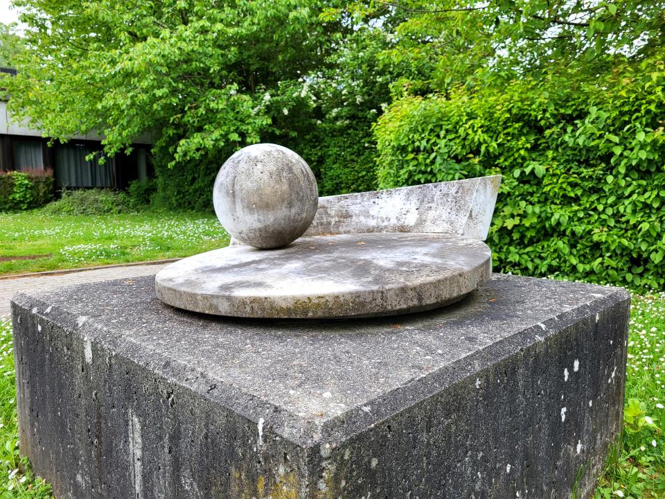 Verwitterte Marmor-Skulptur auf Betonsockel.