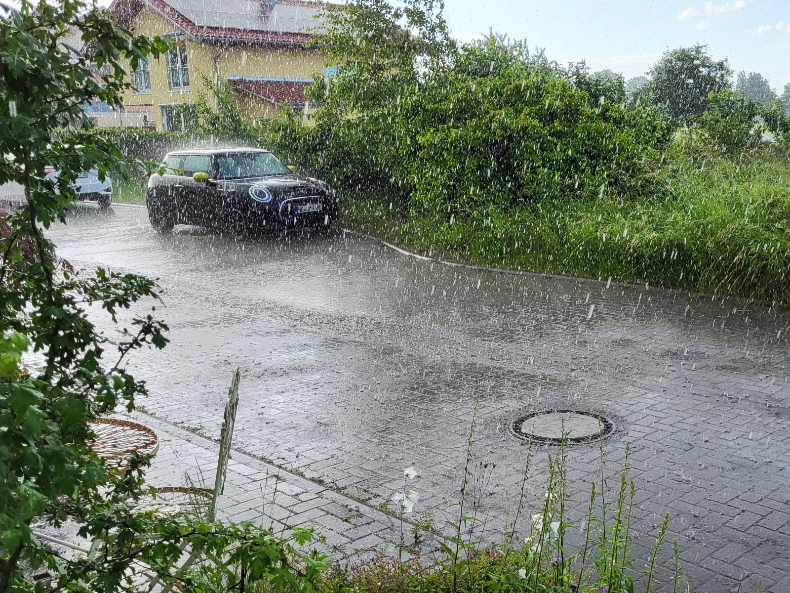 Viele Regentropfen fallen auf eine Straße.