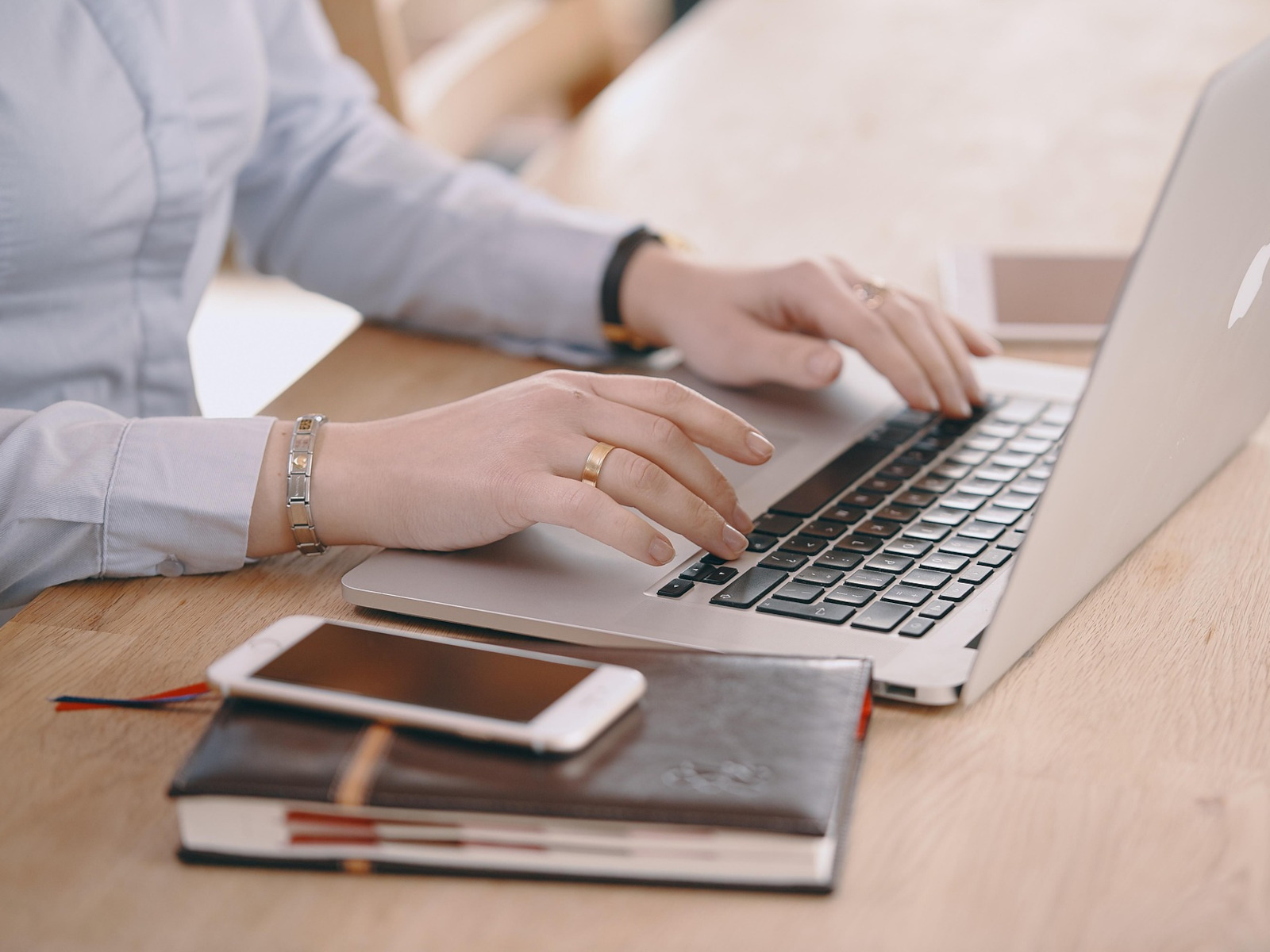 Eine Frau sitzt vor einem Notebook und bedient die Tastatur.