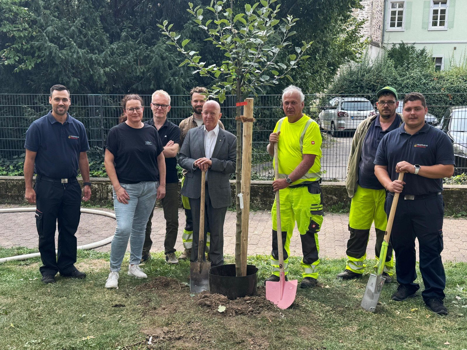 Gruppenfoto vieler Beteiligter mit neuem Apfelbaum in der Amarante-Anlage bei der Stadtbibliothek.