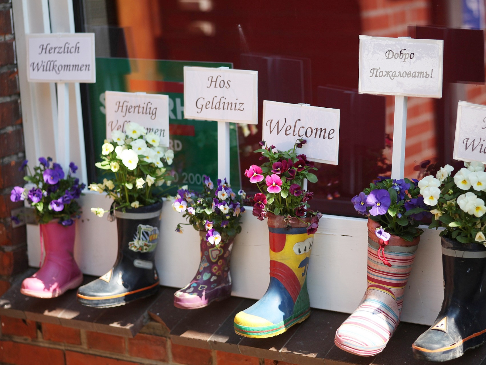 Bunte Gummistiefel und Willkommens-Schilder in verschiedenen Sprachen.
